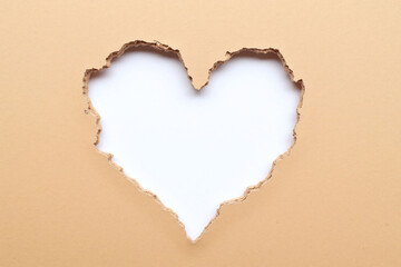 Heart shaped hole in brown paper reveals smooth white surface