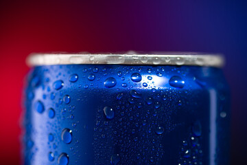 A tin can of cola and a blurry red and blue photo. The top of a tin can of cola