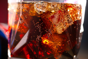 Cola and whiskey in a glass with ice cubes close-up