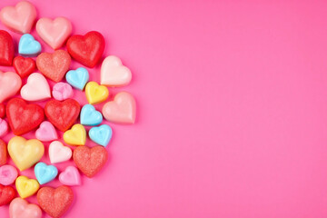 Densely packed heart shaped candies on deep pink background