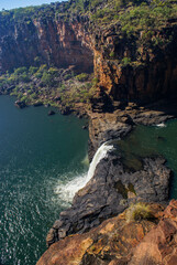 Last cascade of Mitchell Falls flowing down into the lower pool surrounded by red sandstone cliffs, Kimberleys, Western Australia