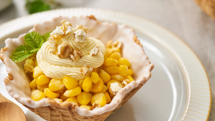 An ice cream cone cup with cream and corn kernels on the inside.
Cream placed on a cream-colored plate All of them were placed on a cream-colored 
dining room table.