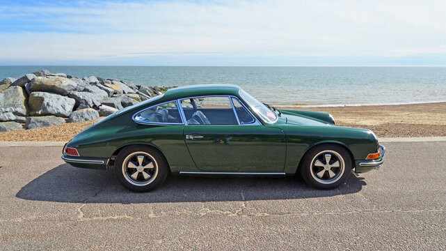 Classic Dark Green Porsche 911 S Coupe parked on seafront promenade beach and sea in background 