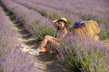 A young girl is sitting in a field of purple flowers, holding a purple flower in her hand. She is smiling and she is enjoying the moment. Concept of happiness and contentment.