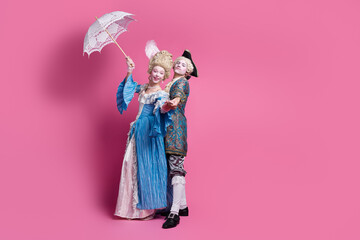 Elegant couple in vintage costumes against a pink backdrop, embodying historical charm and grace at a whimsical masquerade event.