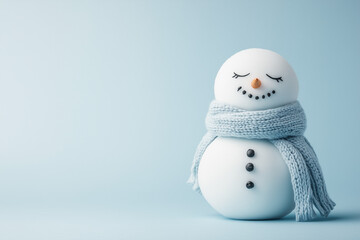 Photo of a sad snowman with closed eyes and wearing a scarf on a light blue background, representing a winter concept.