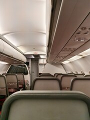 Obraz premium Airplane Cabin Interior with Passenger Seats, Overhead Compartments, and Cockpit View