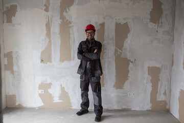 Construction worker with helmet beside gypsum dry wall during apartment reconstruction