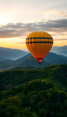 Fototapeta premium A hot air balloon drifts above vibrant green mountains with a volcano in the soft light of dawn.