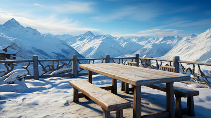 Snow-covered mountain landscape featuring a wooden table and benches with a breathtaking view of distant peaks during a sunny day