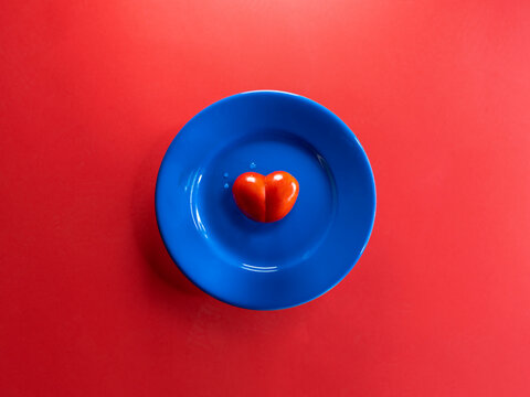 Overhead view of a conceptual heart on a blue plate with a red background