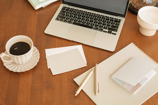 Overhead view of a Home office desk with a coffee cup, open laptop computer with a blank screen and assorted stationery