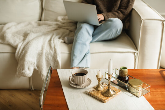 Close-up low section of a woman sitting on a comfortable sofa in a living room using her laptop