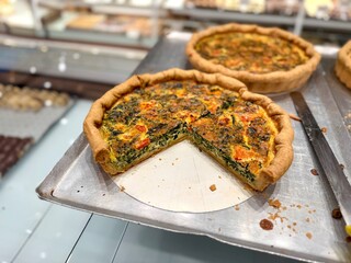 Tasty spinach quiche with tomatoes and cheese at bakery showcase