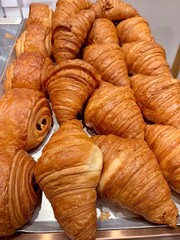 Fresh baked croissants piled on a tray at bakery