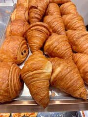 Fresh baked croissants piled on a tray at bakery