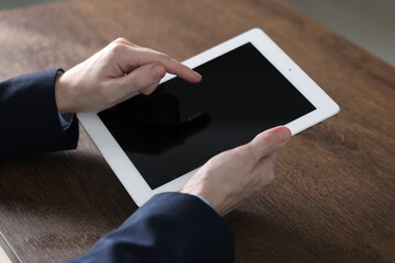 Businessman using tablet at wooden table, closeup. Modern technology