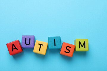 Word Autism made of colorful cubes on light blue background, top view