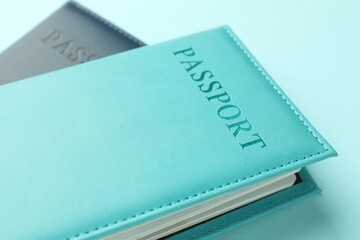 Passports in color covers on light blue background, closeup