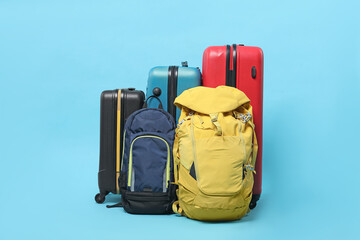 Colorful suitcases and backpacks on light blue background