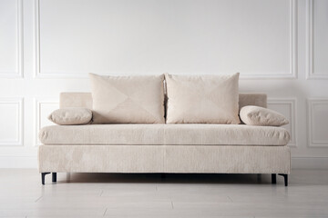 Comfortable sofa with pillows near white wall indoors
