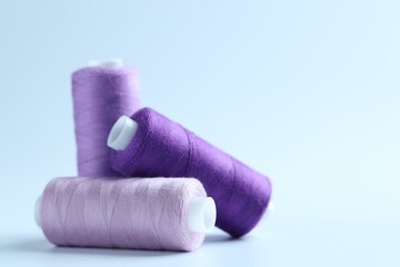 Spools of colorful sewing threads on light background, closeup. Space for text