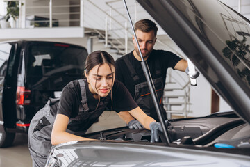 Trying to identify the source of the problem. Two mechanics man and woman working together at open...