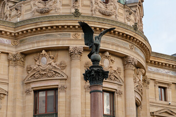 Sculpted eagle perched on column against ornate building facade in European city