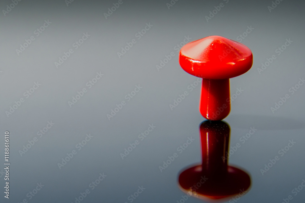 Poster Red pushpin standing upright on a reflective surface with a soft gradient background