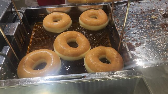 Donuts cooking in a donut fryer.