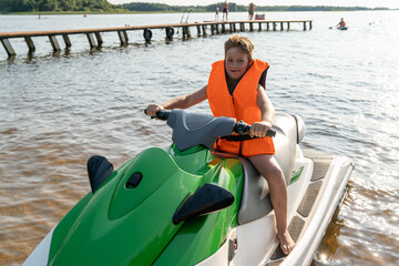 Obraz premium A boy enjoys riding a jet ski on a calm lake