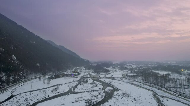 aerial drone pink sunset dusk shot passing over lidder river on the aru srinagar route with cars passing over roads and bridges showing the beauty of kashmir