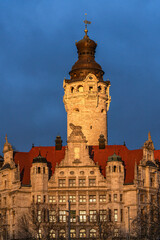Obraz premium Front view of the new town hall in Leipzig. The facade is illuminated by the low sun. Golden evening sun with a dramatically dark sky. Photo taken in winter.