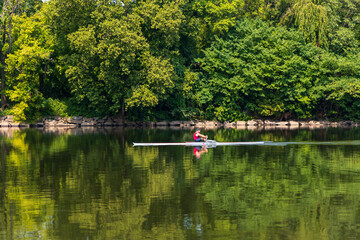 A man in a red boat is rowing across a lake
