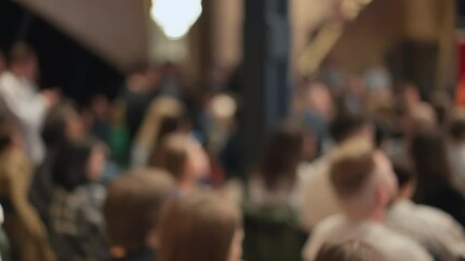 Soft-focused audience attentively observes tech presentation. Image hints at innovation reveal, technology conference. Related to tech startups, innovation showcases, tech event gatherings