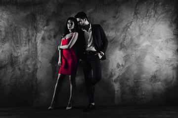 Obraz premium Full size body portrait of attractive couple charming slim lady in purple dress gentlemen in tuxedo holding hand in pocket looking at lover standing near grey wall background