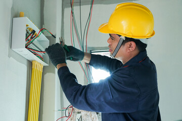 An electrician is using a device to check the electrical current for electrical installation in a home.