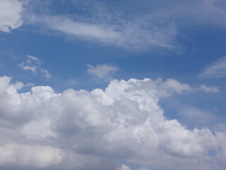Clouds billow across the brilliant blue summer sky like cotton tufts, billowing, puffy, soft, the sky is bright blue and the clouds are white. The sky during the day has pure white clouds like cotton