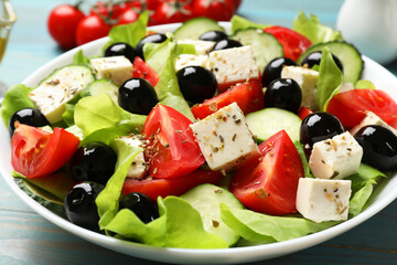 Delicious salad with feta cheese on light blue wooden table, closeup