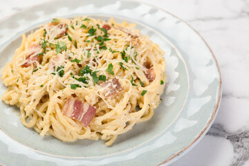 Delicious pasta Carbonara with bacon on white marble table, closeup