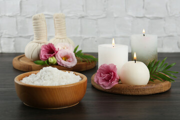 Spa treatment. Massage bags, sea salt, burning candles and flowers on wooden table