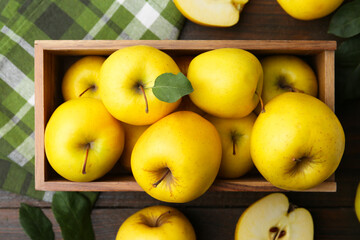 Ripe yellow apples in crate on wooden table, top view