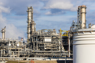 Refinery complex with fuel storage tanks, smokestacks and pipes with dark clouds