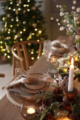 Christmas celebration. Festive table setting with dishware, glasses and decor in room