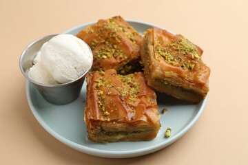 Delicious baklava with crushed nuts and ice cream on beige table, closeup