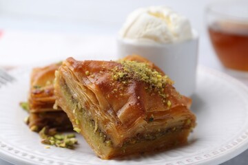 Delicious baklava with crushed nuts and ice cream on table, closeup