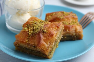 Tasty baklava with chopped nuts and scoops of ice cream on table, closeup