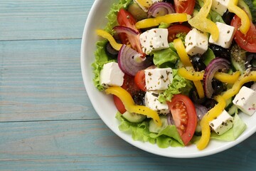 Delicious fresh Greek salad on light blue wooden table, top view. Space for text