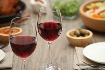 Red wine and delicious dinner served on wooden table, closeup. Space for text