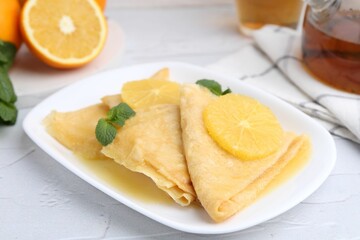 Delicious Crepes Suzette served on white textured table, closeup